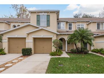 Tan three-story townhouse with two-car garage, landscaping, and palm trees at 3141 Royal Tuscan Ln, Valrico, FL 33594