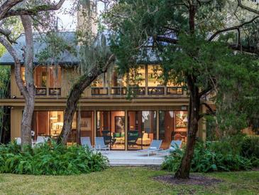 Backyard patio of a two-story home with lush landscaping and large windows at 3348 Old Oak Dr, Sarasota, FL 34239