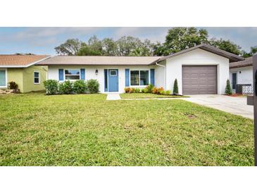 Newly renovated home with a fresh exterior, well-manicured lawn, and attached garage at 8103 San Bernardino Dr, Port Richey, FL 34668