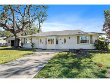 White single story home with gray roof, two doors, and a large tree at 1005 Hines Ave, Sarasota, FL 34237