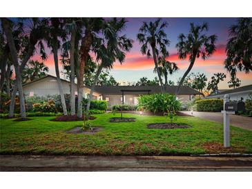 Beautiful home with lush landscaping and palm trees at sunset at 5345 Siesta Ct, Sarasota, FL 34242