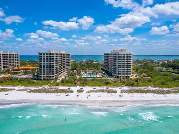 Stunning aerial view of beachfront condos, pool, and lush landscaping at 1211 Gulf Of Mexico Dr # 105, Longboat Key, FL 34228