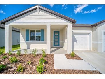 New single-story home with a covered entryway, teal shutters, and a two-car garage at 14010 Ginnie Springs Way, Parrish, FL 34219