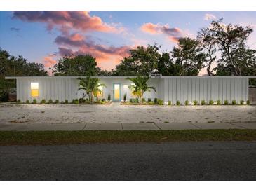 Charming single-story home with a bright white exterior, well-manicured lawn, and beautiful landscaping at 2069 Bougainvillea St, Sarasota, FL 34239