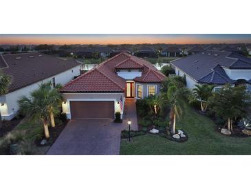 Beautiful single-story home with a red tile roof, manicured landscaping, and a paver driveway at twilight at 4730 Zeno Ct, Bradenton, FL 34211
