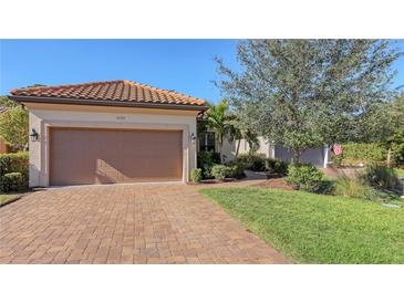 Inviting front yard with a paved driveway, attached garage, and lush landscaping at 5737 Semolino St, Nokomis, FL 34275