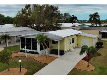 Charming yellow home with a manicured lawn, mature trees and landscaping at 8411 Regal Way, Palmetto, FL 34221