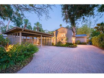 Charming home with a brick driveway, carport, and lush landscaping at dusk at 1656 Hillview St, Sarasota, FL 34239