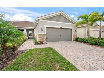 Single-story home with gray siding, stone accents, and a paved driveway at 8792 Rain Song Rd, Sarasota, FL 34238