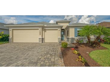 Two-car garage, light beige exterior, landscaping, paver driveway at 12305 Goldenrod Ave, Bradenton, FL 34212