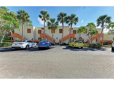 Light beige condo building with wood accents, palm trees, and ample parking at 141 Wild Palm Dr, Bradenton, FL 34210