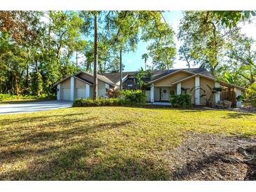 Tan house with a two-car garage and lush landscaping at 5131 Willow Leaf Dr, Sarasota, FL 34241