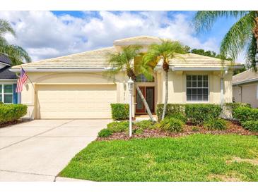 Charming single Gathering home showcasing a well-manicured lawn, a two-car garage, and beautiful tropical landscaping at 8412 Whispering Woods Ct, Lakewood Ranch, FL 34202