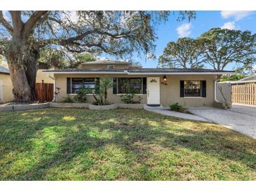 Tan house with a large tree, landscaped lawn, and black shutters at 2538 Floyd St, Sarasota, FL 34239