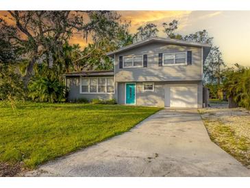 Gray house with teal door, driveway, and grassy yard at 3135 Alta Vista St, Sarasota, FL 34237