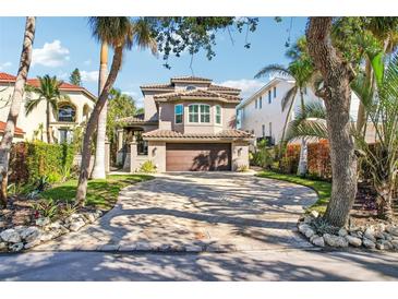 Elegant two-story home with a paver driveway, tile roof, and well-manicured landscaping surrounded by mature trees at 5159 Oxford Dr, Sarasota, FL 34242