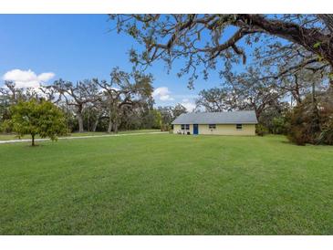 Yellow house with blue door, large yard, and mature oak trees at 6706 16Th E Ave, Palmetto, FL 34221