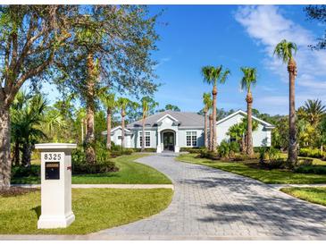 Luxury home with circular driveway, lush landscaping, and palm trees at 8325 Lindrick Ln, Bradenton, FL 34202