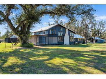 Dark-painted farmhouse with screened porch, surrounded by lush green lawn and mature trees at 14900 Coker Gully Rd, Myakka City, FL 34251