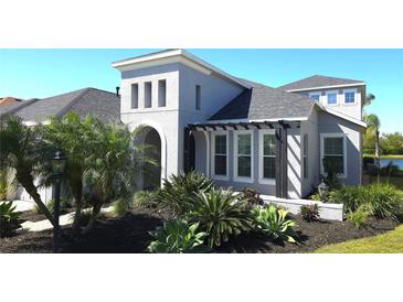 Beautiful home featuring a stucco exterior, arched entry, pergola and attractive landscaping with mature trees and plantings at 4742 Balboa Park Loop, Bradenton, FL 34211