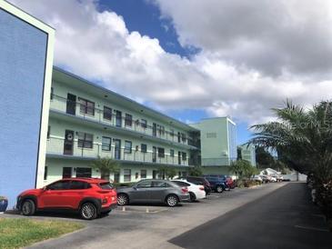 Multi-story condominium building with parking area and tropical landscaping at 5973 Terrace Park N Dr # 208, St Petersburg, FL 33709