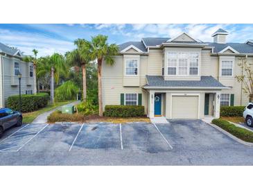Tan two-story townhome with a teal door, two parking spots, and lush landscaping at 7664 Plantation Cir, Bradenton, FL 34201