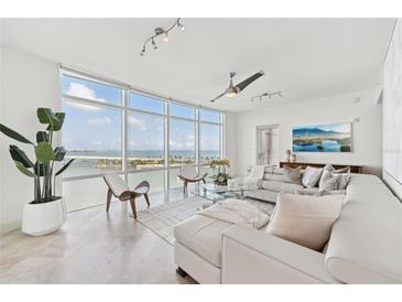 Bright living room features floor-to-ceiling windows with stunning water views and a comfortable white sectional sofa at 258 Golden Gate Pt # 801, Sarasota, FL 34236