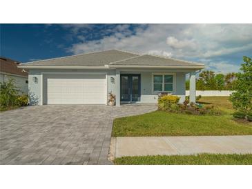 One-story home with white garage door, gray paver driveway, and landscaped lawn at 5252 Willow Lake Ct, Sarasota, FL 34233