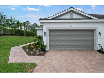 This home has a lovely exterior with a gray garage door and a brick paver driveway and walkway at 6005 Mesa Gln, Bradenton, FL 34203