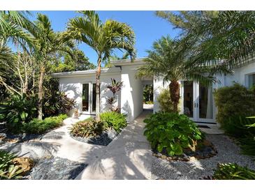 Landscaped entry with tropical plants and a walkway leading to the home's entrance at 6061 Gulf Of Mexico Dr, Longboat Key, FL 34228