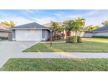 Charming single-story home featuring a well-manicured lawn, palm trees, and a two-car garage at 4877 Post Pointe Dr, Sarasota, FL 34233