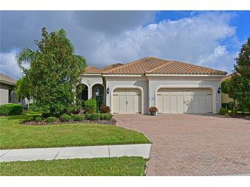 Charming two-car garage home featuring a well manicured lawn, lovely landscaping and a paver driveway at 963 River Wind Cir, Bradenton, FL 34212