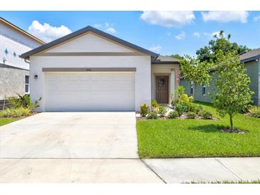 Newly constructed home with a white exterior, two-car garage, and landscaped front yard at 9016 Waxwing Way, Parrish, FL 34219