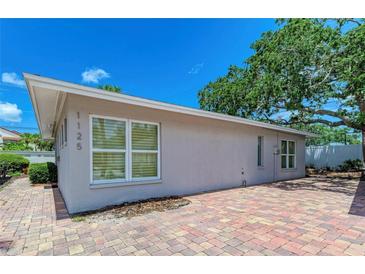 House exterior showcasing a light gray color, brick pavers, and lush landscaping at 1125 N Moonmist Ct # L5, Sarasota, FL 34242
