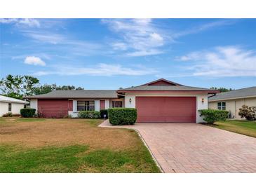 Ranch-style home with red siding, brick driveway, and well-manicured lawn at 4423 Meadow Creek Cir, Sarasota, FL 34233