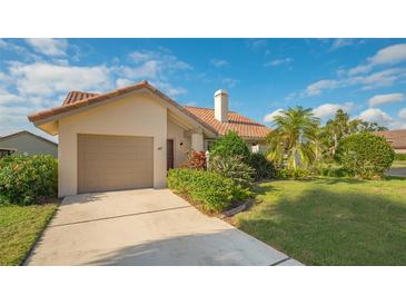 Tan one-story house with tile roof, attached garage, and landscaped yard at 47 Inlets Blvd # 47, Nokomis, FL 34275