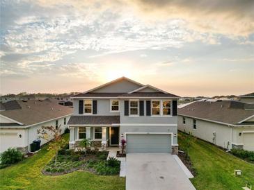 Two-story home with manicured front yard, three-car garage, and pond view at 5225 Grove Mill Loop, Bradenton, FL 34211