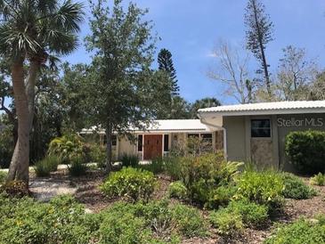 Landscaped front yard with lush plants surrounding a single-story house with a light-colored exterior and stone accents at 640 Venice Ln, Sarasota, FL 34242