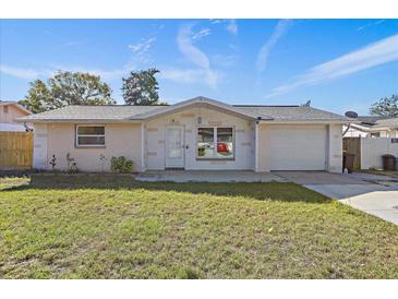 House exterior featuring a white brick facade, attached garage, and well-maintained lawn at 7720 Judith Cres, Port Richey, FL 34668