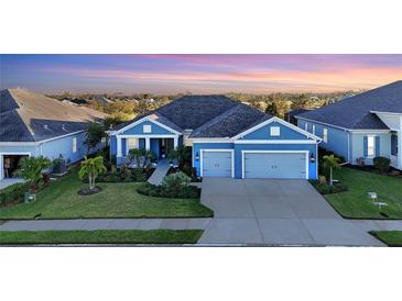 Stunning curb appeal! This beautiful blue home features a welcoming porch and lush landscaping at 13930 Old Creek Ct, Parrish, FL 34219