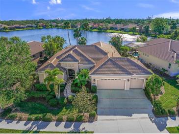 Stunning lakefront home featuring manicured landscaping, a three-car garage, and a tile roof at 518 Luminary Blvd, Osprey, FL 34229