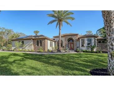 Charming home showcasing the landscaped front yard with palm tree and decorative stone and stucco exterior at 1609 Palm View Rd, Sarasota, FL 34240