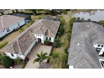 Expansive home with a tile roof, lush landscaping, and a tranquil pond view in a desirable neighborhood at 16907 Verona Place, Lakewood Ranch, FL 34202