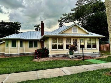 Charming yellow house with metal roof, landscaping, and walkway at 213 Durrance St, Punta Gorda, FL 33950