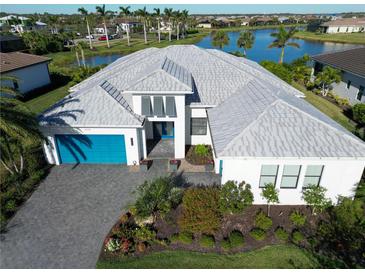 Stunning aerial view of a modern home with lush landscaping and a beautiful lake view at 4779 Pastel Ct, Sarasota, FL 34240
