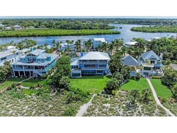 Stunning coastal home with manicured lawn, mature palms, and boat dock access on a waterway at 506 S Casey Key Rd, Nokomis, FL 34275