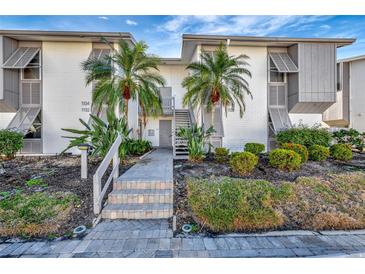 Inviting condo building with lush landscaping and a walkway leading to the entrance at 1130 W Peppertree Ln # 118, Sarasota, FL 34242