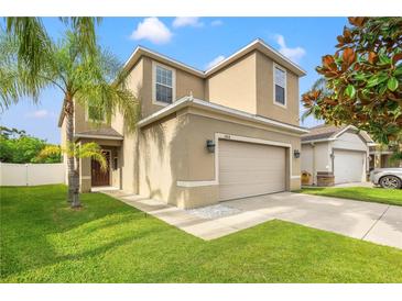 Two-story house with beige exterior, two-car garage, and manicured lawn at 1964 Hawks View Dr, Ruskin, FL 33570