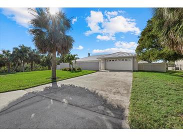 Charming single story home with lush landscaping, green lawn, and a concrete driveway at 5164 Windward Ave, Sarasota, FL 34242