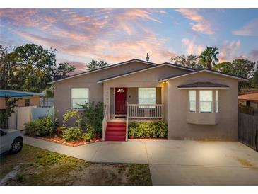 Tan house with red door, landscaping, and driveway at 4704 Town N Country Blvd, Tampa, FL 33615